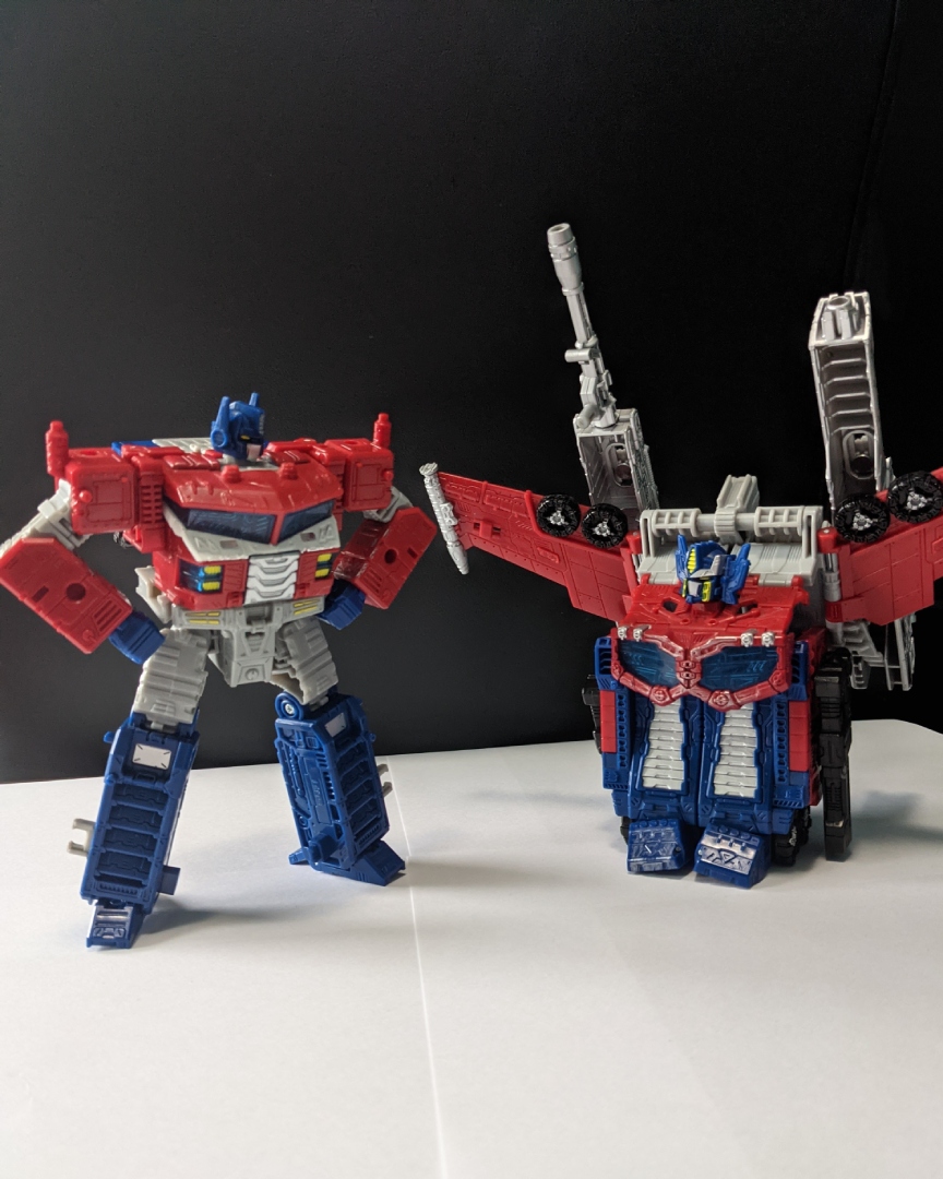 A picture of Galaxy Upgrade Optimus Prime, with his inner robot mode posed comically next to a loose amalgamation of his spare 'super mode' components.