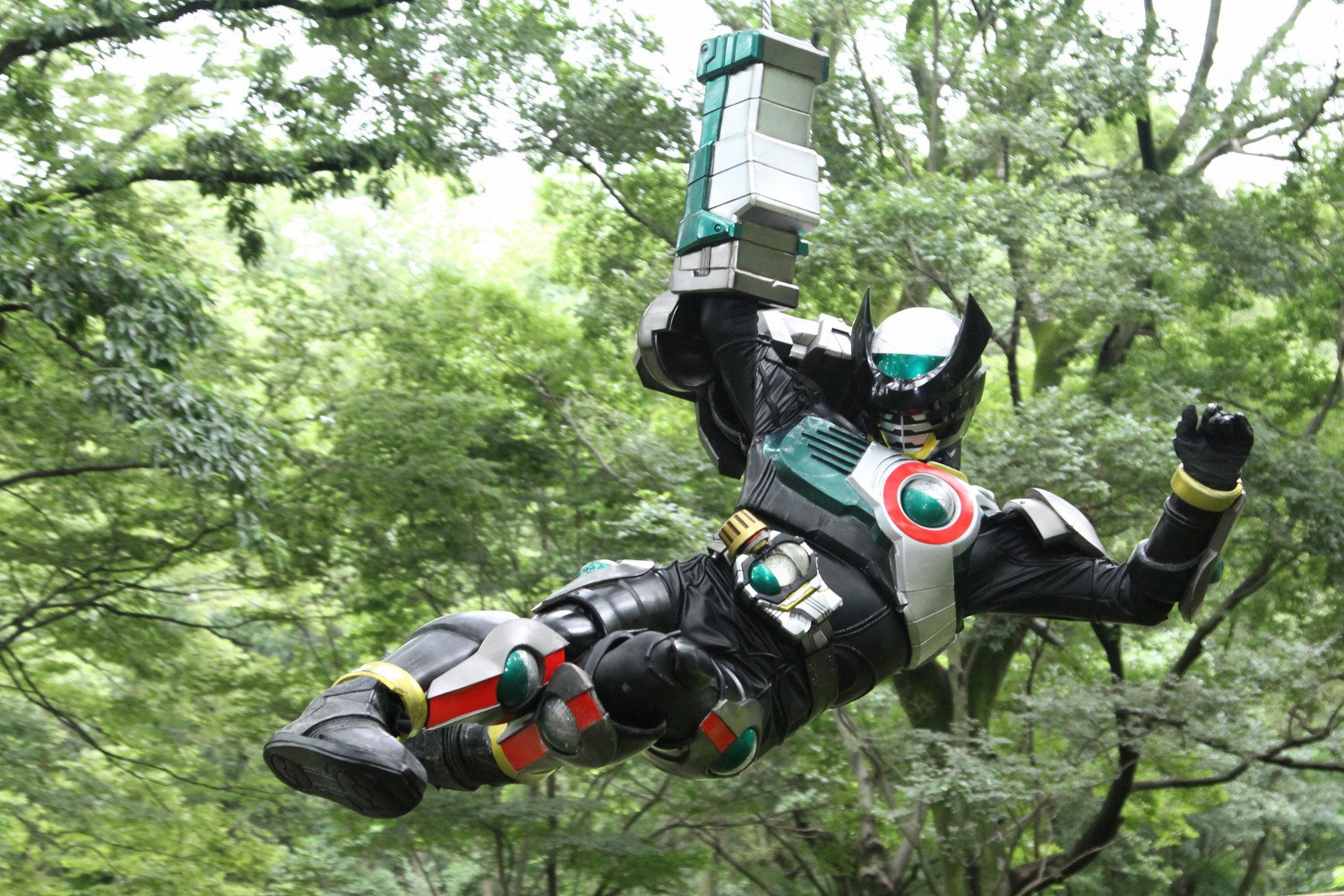 we're just doing the basics! so to understand Kamen Rider Birth, you just gotta know that there were these alchemists 800 years ago, and they made these mummies, and the mummies were made out of coins, and the whole thing's a multi-layered metaphor for capitalism, depression, and disability. and then there's a dude who fucking LOVES baking cakes. A production shot of Kamen Rider Birth Prototype, swinging from his Crane Arm to perform a kick.
